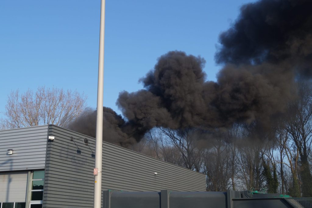 Grote brand in leegstaand pand op industrieterrein, zwarte rook boven A20